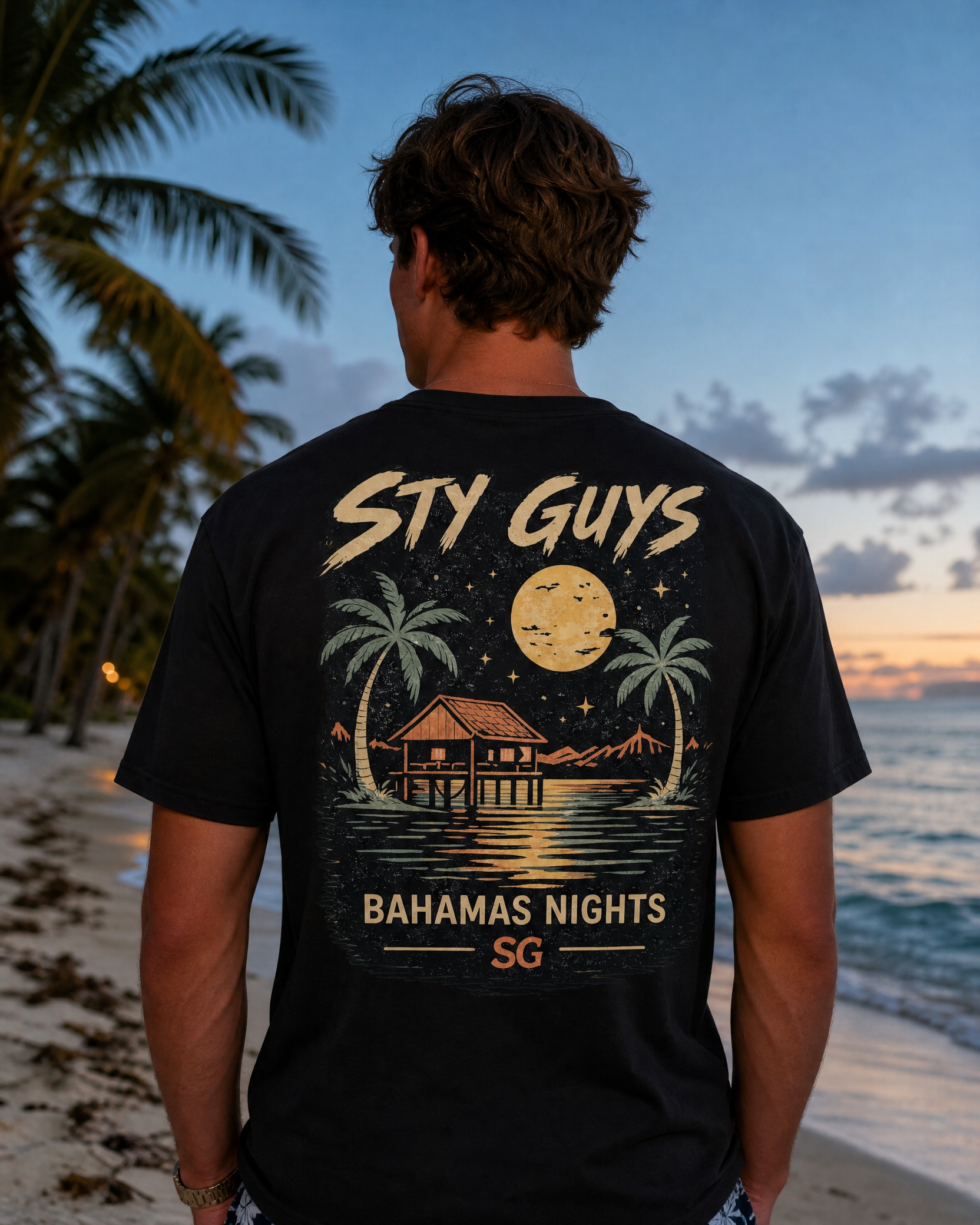 Man wearing the Bahamas Nights tee, Beach colorway, moonlit stilt house back print