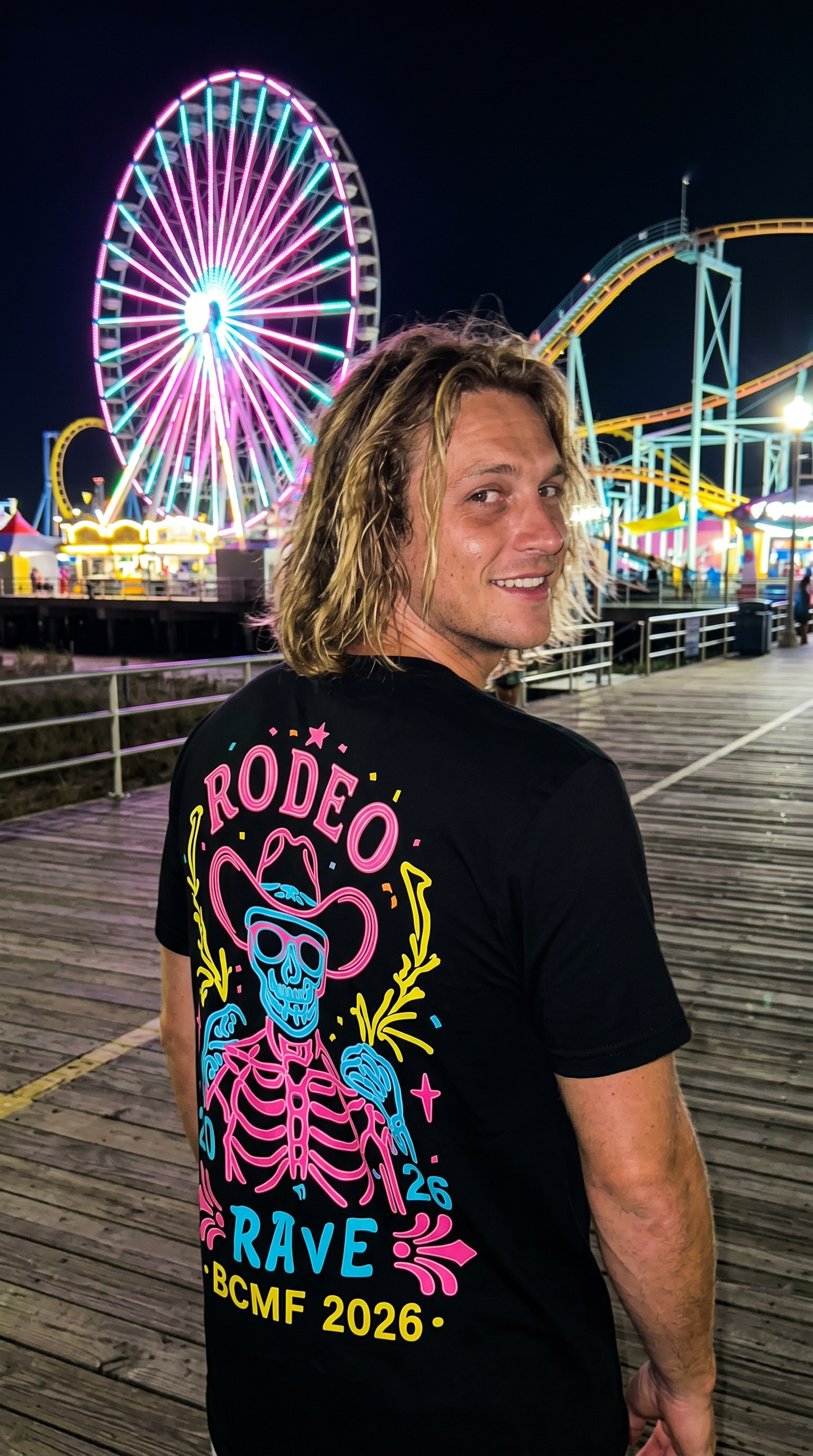 Man wearing black Rodeo Rave back print tee on Wildwood boardwalk at night