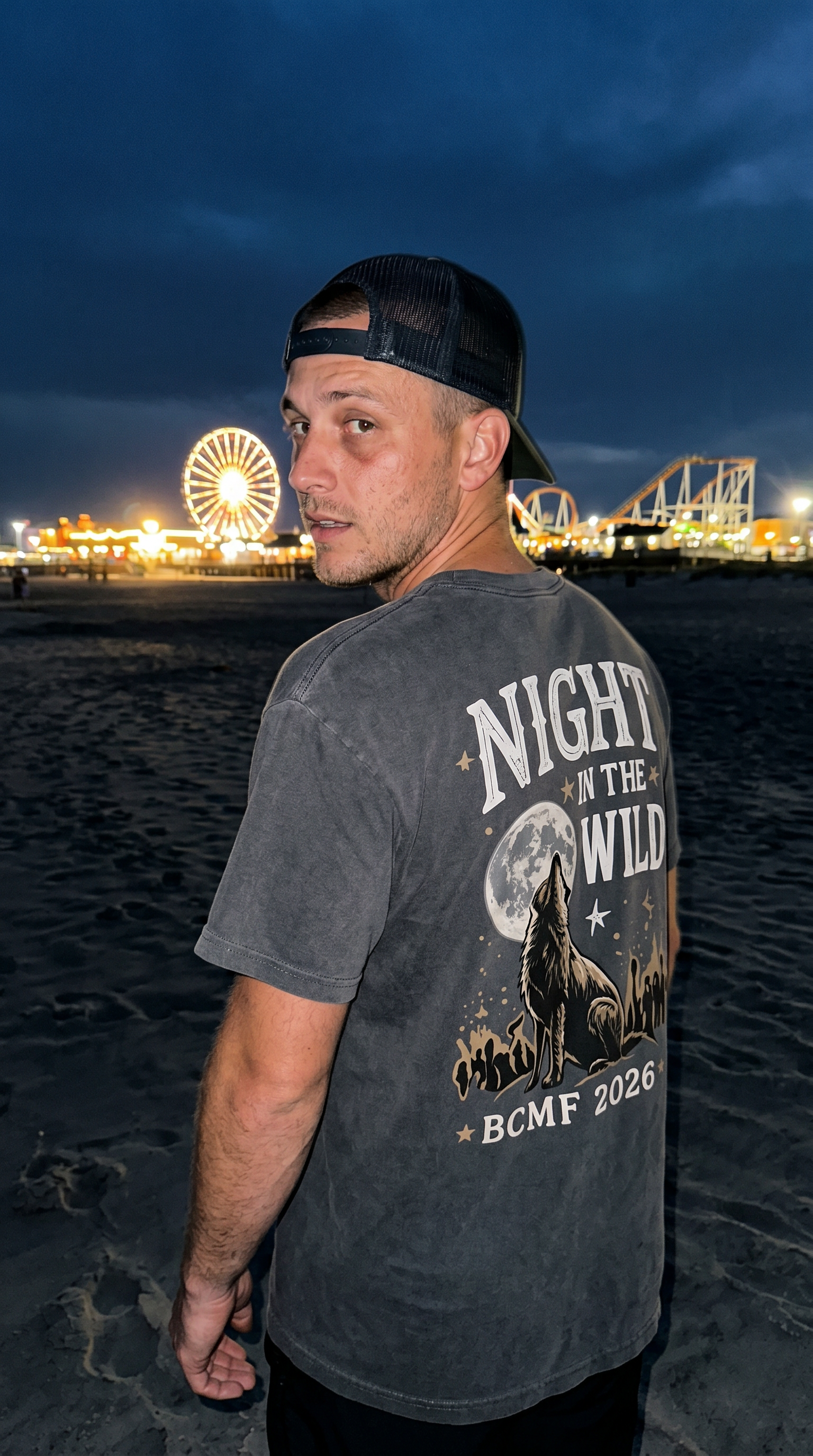 Man wearing charcoal Night in the Wild back print tee on dark Wildwood beach